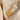 A gold-colored pendant necklace with a circular charm displayed on a fabric surface.