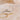 Two necklaces, one gold and one silver, on a sandy surface with seashells in the background.