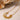 A gold-colored necklace with a sunburst design, featuring a central circular charm with a sparkle, surrounded by a chain.