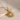 A gold-colored pendant necklace with a sun and moon design, featuring small diamonds, displayed on a textured background.