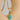 Gold chain necklace with a turquoise pendant on a beige background