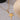 A gold-colored necklace with a star-shaped pendant on a beige background.