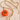 Gold necklace with a small orange pumpkin pendant on a beige surface