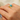 Gold ring with a turquoise stone on a person's finger against a neutral background
