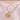 Gold necklace with a pendant on a soft pink background