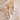 Gold and pearl earrings on a beige stone surface