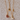 Two gold necklaces with heart-shaped pendants on a textured beige surface