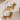 Gold hoop earrings with colorful beads and leaf charms on a textured white surface