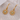 Gold sunflower-shaped earrings on a textured surface