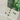 Gold necklace and earrings with green clover-shaped stones on a white card, with green glass bottles in the background.