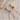 Two necklaces, one with a gold chain and a green pendant shaped like a heart, and the other with a silver chain and a similar green pendant.