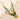 A gold-colored necklace with green beads and a hammered disk pendant laid out on a white surface.