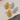Pair of gold and silver woven earrings on a textured surface.