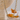 A wavy chain necklace in gold color displayed on a stand with a blurred background.