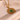 Gold pendant with a green gemstone on a beige fabric background