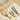 Three necklaces with colorful beads and gold accents on a beige surface