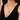 Gold necklace with a pendant worn by a person in a black top.