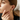 Woman wearing gold earrings and ring, focusing on the jewelry.