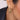 Close-up of an ear wearing a gold and silver feather-shaped earring.