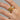 Gold rings with gemstones on a hand against a neutral background