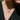 Gold necklace with a pendant on a person wearing a black pinstripe suit.