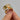 Gold ring with multicolored gemstones held by a hand against a gray background