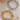Two chain bracelets, one gold and one silver, on a textured surface.