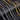 Collection of gold, silver, and iridescent chain necklaces on a black textured background