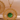 Gold pendant with a green gemstone on a beige background