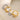 Two rings, one gold and one silver, with embedded stones on a beige background