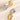 Four rings in gold and silver on a textured beige surface