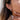 Close-up of a person wearing gold hoop earrings with a neutral background