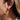 Close-up of an ear wearing a gold hoop earring with clear stones.