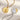 Two gold and silver necklaces with intricate designs on a textured beige surface.