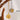Two gold and silver necklaces with medallions on a wooden stand.
