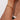 Gold bracelet on a person's wrist with a neutral background