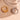 Gold and silver rings on a beige surface with a glass bowl in the background