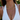 Woman wearing a white dress with gold chain necklaces against a blurred natural background