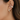 Close-up of an ear wearing gold hoop earrings with clear stones.