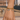 Gold chain bracelet with heart and square charms on a wrist against a blurred outdoor background