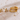 Gold earrings and rings on a textured surface with blurred floral background