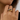 Close-up of a hand wearing two gold rings on a neutral background
