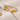 Gold bracelet on a white surface with a magazine