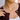 Gold necklace with charms worn by a person, close-up on neck and chest.
