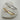 Two diamond-studded bangles, one gold and one silver, on a white stone surface.
