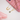Gold necklace with a blue pendant on a pink phone case and gloves.