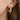 Gold hoop earring with embedded stones worn by a person
