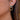 Gold earring with a blue gemstone worn by a person