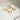 Gold hoop earrings shaped like stars and hearts on a light surface with a glass object in the background.