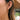 Close-up of an ear wearing a gold earring with small charms.